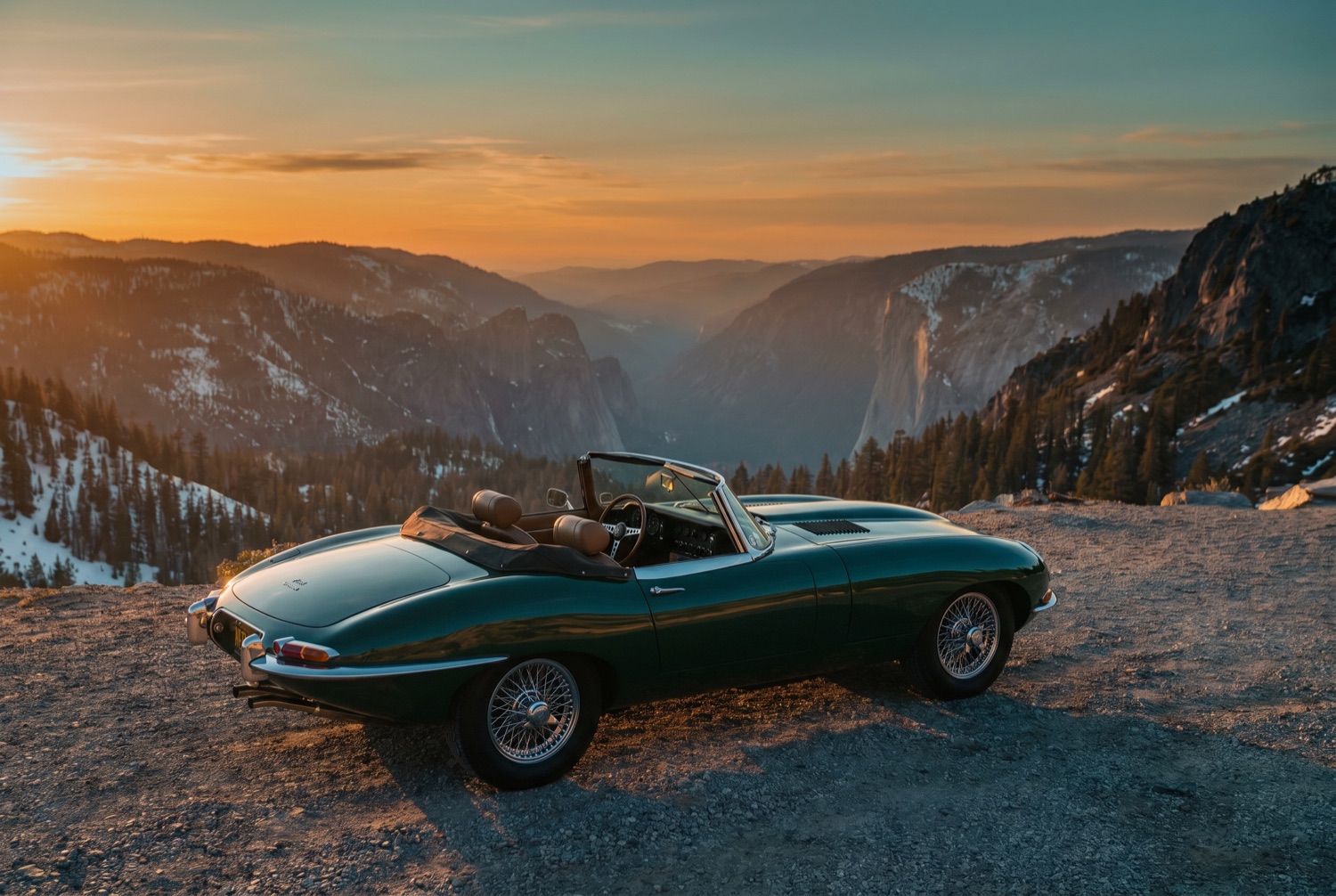 A classic roadster parked at a quiet alpine overlook in golden light